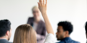 woman raising her hand to ask a question